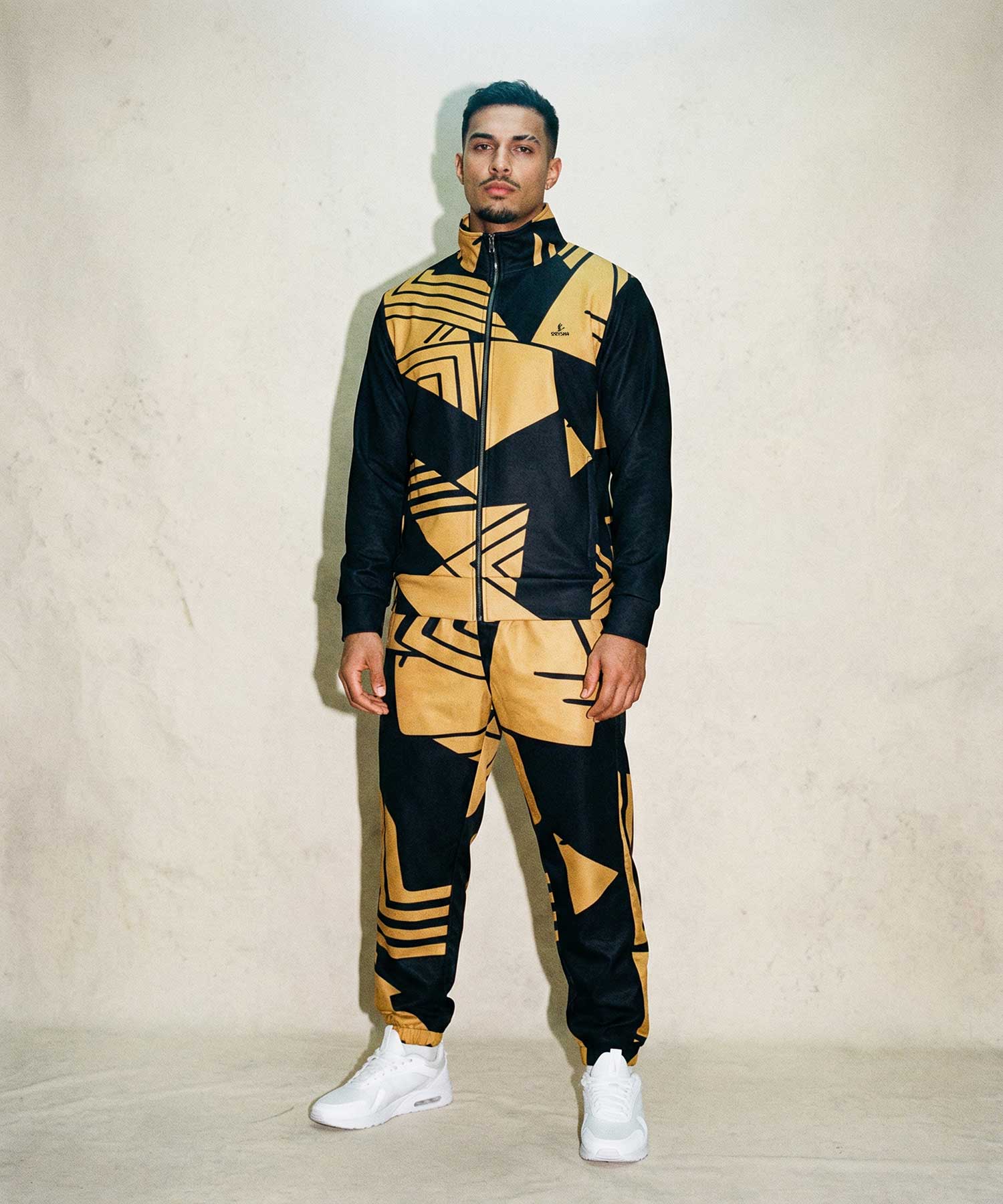 Person wearing a black and yellow geometric patterned tracksuit against a plain background