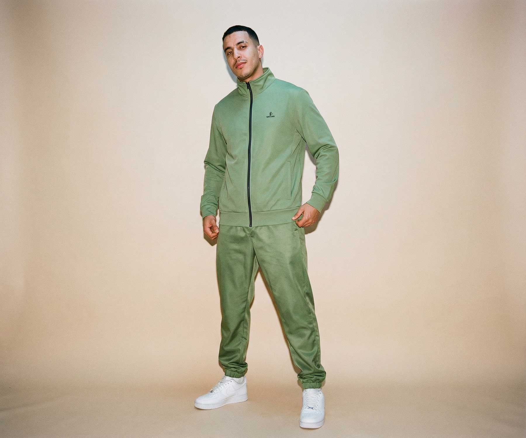 Man wearing a green tracksuit against a beige background