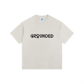 Beige t-shirt with 'GROUNDED' text on a white background